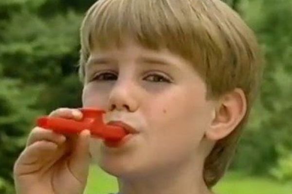 A young boy enthusiastically playing the Kazoo